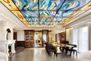 תקרת ויטראז' ,זכוכית מחוסמת בבית יוקרה בירושליים,מנורות קודש מרהיבות מזהב בויטרינות וספרים שולחן אוכל אח בוער ,נברשות אור מעל שולחן האוכל.