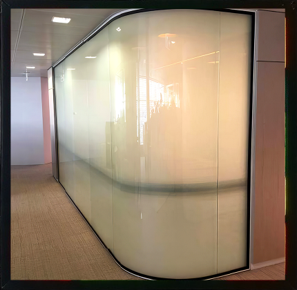 קיר זכוכית חלבית מעוקל במסדרון משרדי, עם השתקפויות עדינות ותאורה רכה, המפריד בין חללים תוך שמירה על עיצוב מודרני, נקי ומינימליסטי.