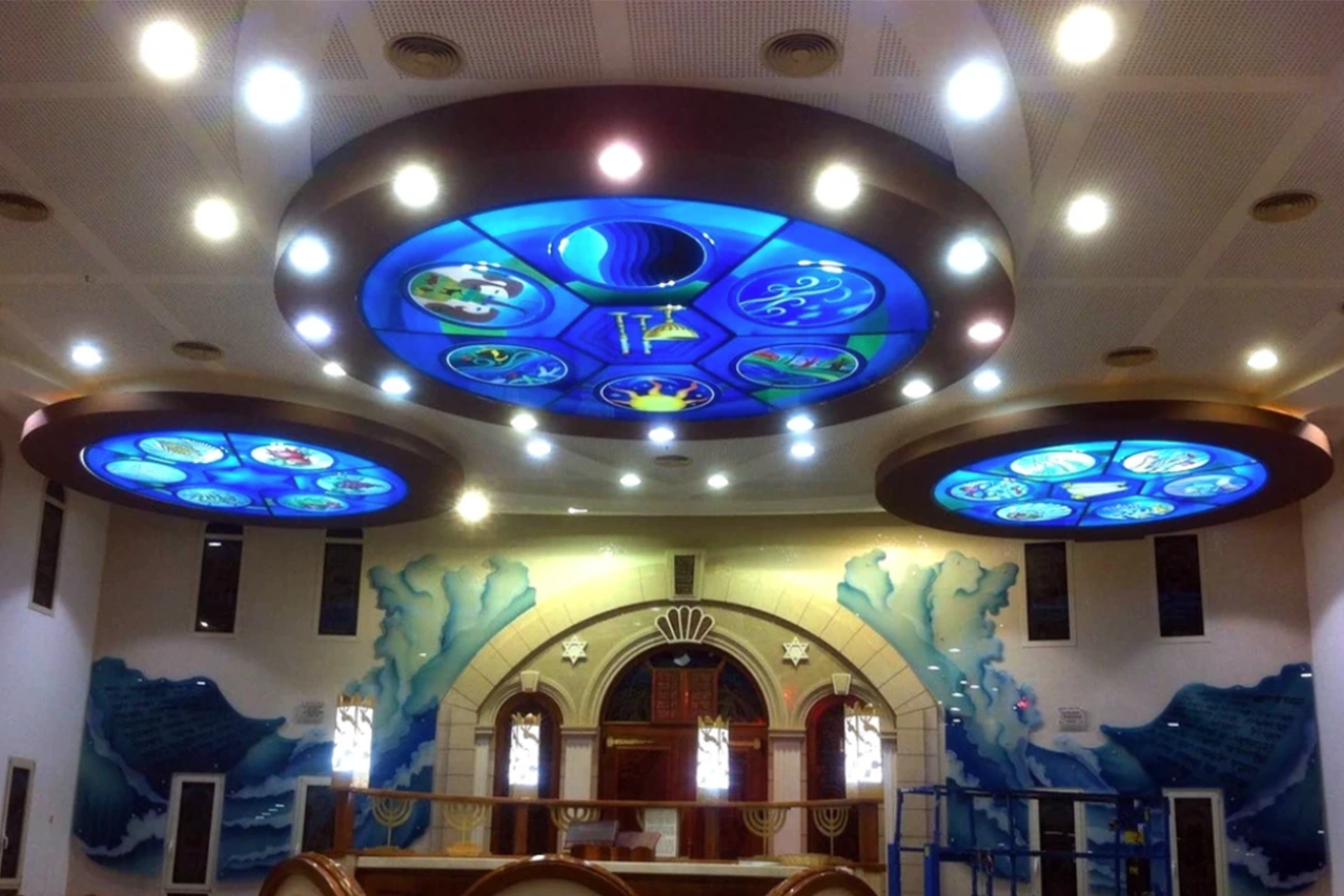 חדר מואר היטב, ובו שלושה לוחות תקרה עגולים גדולים עם רקע כחול וסמלי גלגל המזלות, מעל חלונות מקושתים וציורי קיר בהשראת הים.